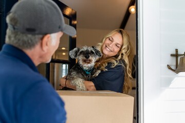 Woman receiving package delivery, holding a dog image