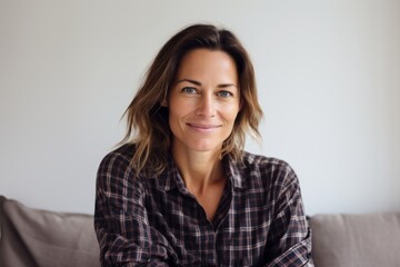Obraz premium Portrait of a smiling woman in her 40s dressed in a relaxed flannel shirt isolated on modern minimalist interior