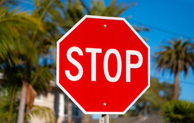 Red and white stop sign on a side road in Carpinteria, California. Bright and reflective colors of traffic sign in the warm evening light. International sign for “STOP” at an intersection or junction.