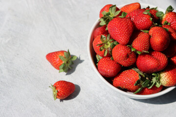 Strawberries in a white bowl on a light background, top view