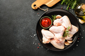 Chicken wing, raw chicken meat with herbs. Top view with copy space on black table.