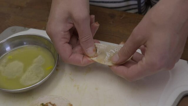 This time lapse video shows a wonton dumpling being made by hand from beginning to end.