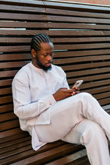Fototapeta premium Millennial generation african american man typing sms outdoor 5g internet concept. High speed internet on phone and chatting on social networks and blog concept