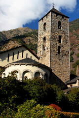 Photo with a view of Sant Esteve d'Andorra church illuminated by sunlight against the background of mountains in the city of Andorra la Vella, Principality of Andorra	