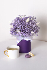 
Bouquet of beautiful violet flowers in box with tea and lavender macaroons
