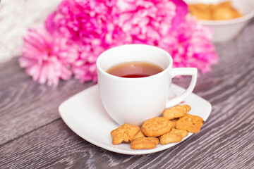 
Sweet morning breakfast - cup of tea, cookies and bouquet of peonies flowers
