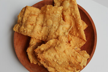 Kerupuk pangsit, or crispy fried thick skin dumpling, inside a white bowl, isolated in white background, flat lay or top view