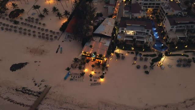 Amazing aerial view, captured by drone, reveals coastal city at dusk. City below is illuminated by sparkling lights, creating captivating sight. This popular tourist destination Punta Cana, Dominican