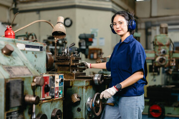 Portrait happy engineer worker with safety eyes protection glasses professional working with metal lathe milling machine heavy industry factory.