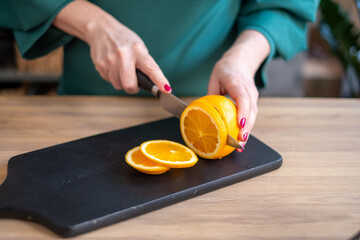 Carefully preparing slices of orange, a woman in a kitchen sets the stage for a refreshing recipe,...
