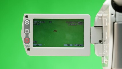 Old vintage video camera close-up. Popular retro camcorder shooting. Chroma key green screen on video-camera monitor.