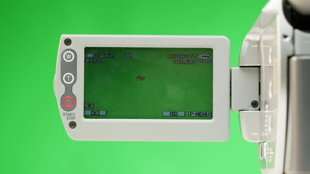 Old vintage video camera close-up. Popular retro camcorder shooting. Chroma key green screen on video-camera monitor.