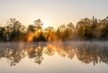 Obraz premium Fog illuminated by rays of rising sun over ponds