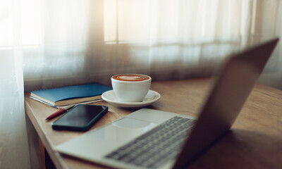 Working space on wooden table. coffee cup with laptop and mobile phone near window have white curtain. vintage color tone