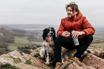 Man sitting with dog on mountain photo