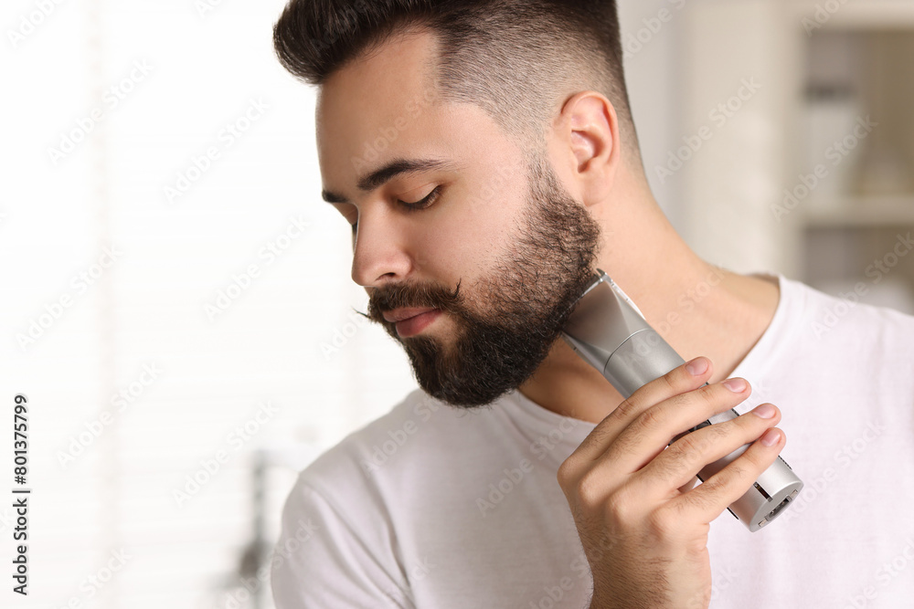 Sticker Handsome young man trimming beard at home