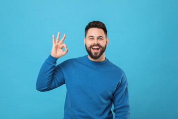 Happy young man with mustache showing OK gesture on light blue background