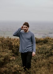 Man wearing long sleeve shirt, walking on hill