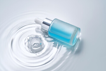 Bottles of cosmetics with a dropper in water on a blue background.