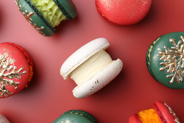 Beautifully decorated Christmas macarons on red background, flat lay
