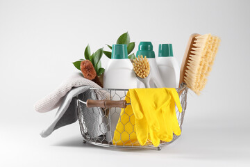 Set of different cleaning supplies in basket on white background