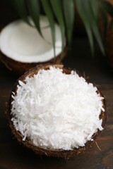 Coconut flakes in nut shell on wooden table