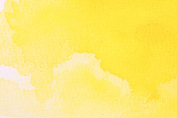 Abstract yellow watercolor painting on white paper, top view