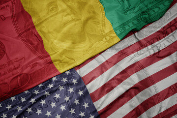 waving colorful flag of united states of america and national flag of guinea on the dollar money...