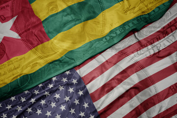 waving colorful flag of united states of america and national flag of togo on the dollar money...