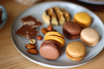 Cup of tea or coffee, cookies, macaroons, chocolate, various nuts and cocoa powder on wooden table. Selective focus.