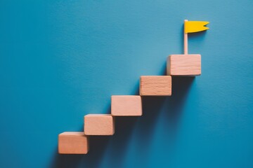 Wooden blocks in ascending order with yellow flag on top against blue background, resembling stairs