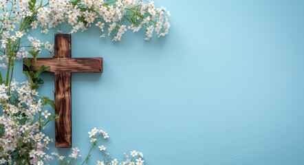 Wooden cross with white flowers on a blue background, depicting a copy space concept for Easter celebration and welcoming the spring season.