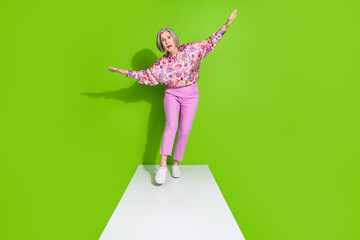 Full length photo of shocked confident lady dressed pink shirt walking path arms sides empty space isolated green color background
