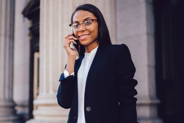 Portrait of successful female office worker dressed in formal wear communicating on...