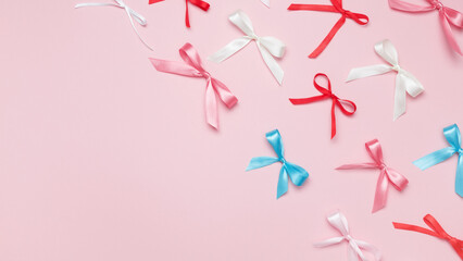 Multicolored bows on pink background. Top view, copy space
