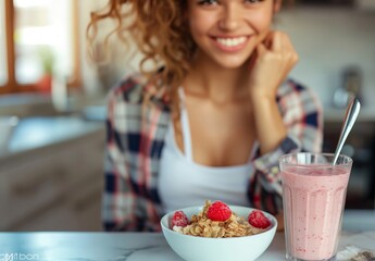 Glowing young woman savors a bowl of granola with raspberries and a fresh strawberry smoothie in a sun-drenched kitchen - obrazy, fototapety, plakaty