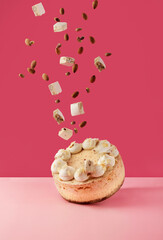 nougat cheesecake with almonds and nougat in the air on pink background