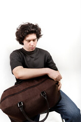 young man sitting with travel bag in studio