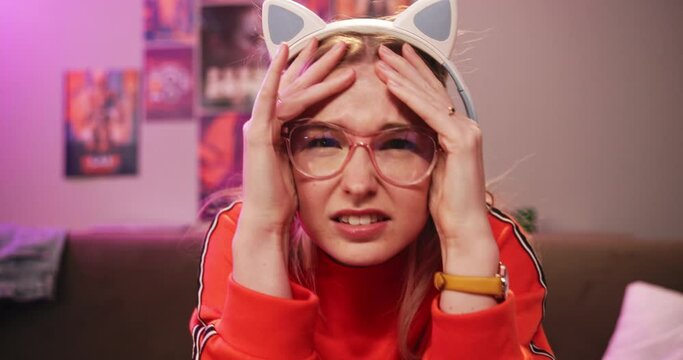 Gamer, lose and headache with competition, esports and stress or mistake. Woman, rage and technology with neon, lounge and apartment or home living room with console frustration and glasses for play