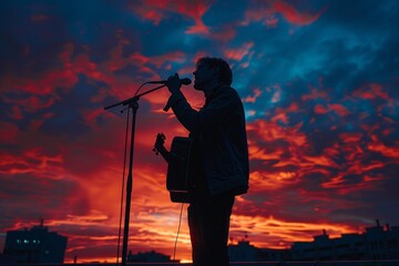 A man singing into a microphone in front of a sunset