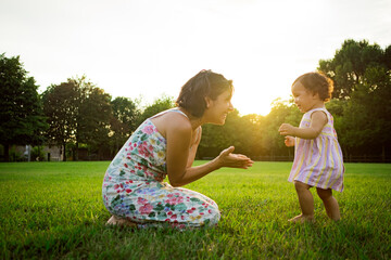 Young mother and daughter playing outdoors on the grass in nature on a summer sunset .concept of...