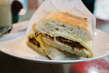 Cheese Bacon and Egg Roll with Turkish Panini bread and Halal Beef Bacon on plate, cut in half
