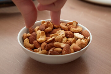 Fingers reaching for nuts in a plate, beer snacks, appetizer in a bar, nuts in a plate