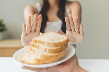 Gluten allergy, asian young woman hand push out, refusing to eat white bread slice on plate in...