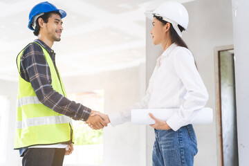Obraz premium Engineer team building, teamwork contractor, two asian young partnership, builder agreement handshake plan home project contract at construction site .Happy architect, surveyor worker shaking hand.