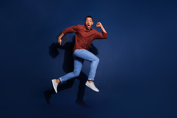 Full length photo of attractive funny guy wear formal shirt jumping high hurrying emtpy space...