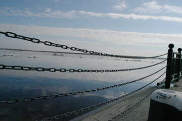 fence on the embankment made of chains. Ice drift on the river.