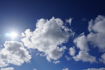 beautiful blue sky with bright sun and fluffy clouds