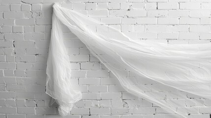   A white cloth against a brick wall, with a brick wall both in front and behind it