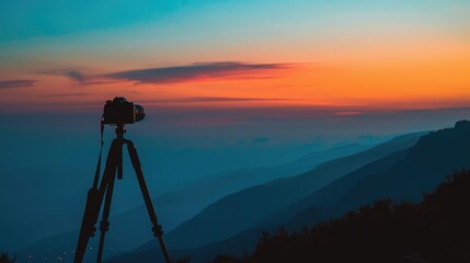 Paint a visual of the silhouette of a camera mounted on a tripod, set against the smooth gradient of orange and blue dawn sky